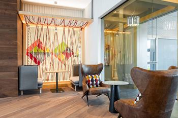 A lobby with chairs and a table in front of a glass door